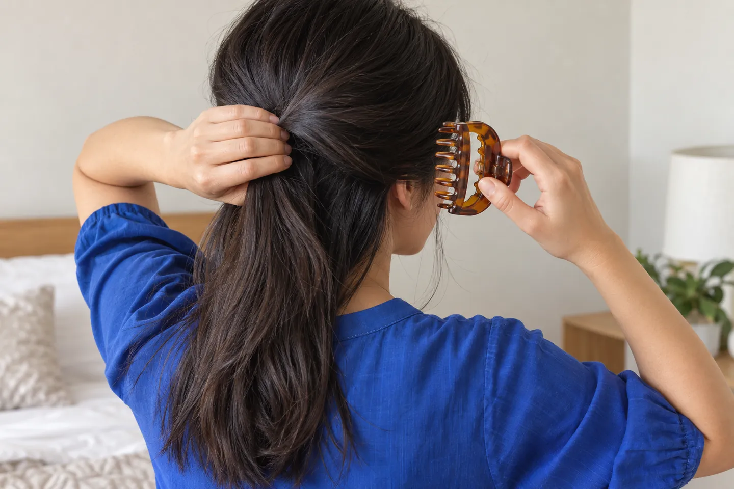 Pessoa adulta apoia uma dobra frouxa de cabelo escuro com uma mão e segura uma piranha âmbar aberta ao lado