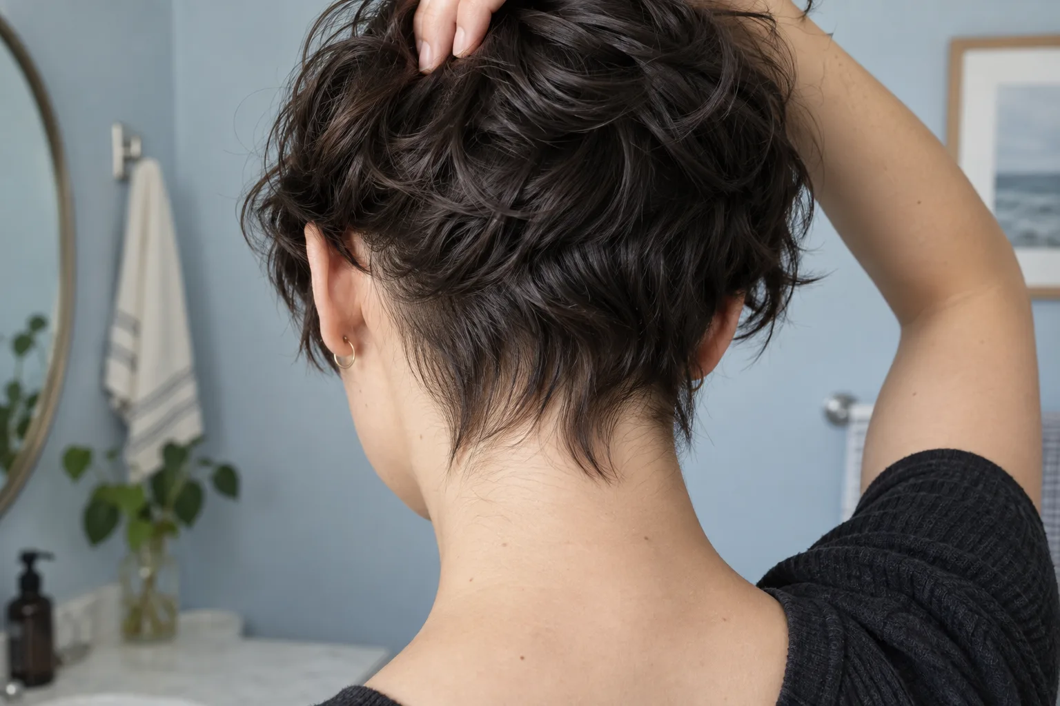 Rückansicht eines herauswachsenden gewellten Pixie Cuts; das Deckhaar ist angehoben und die längere Nackenpartie sichtbar